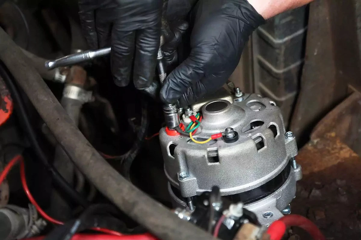 Alternator wiring being installed with a socket and ratchet.