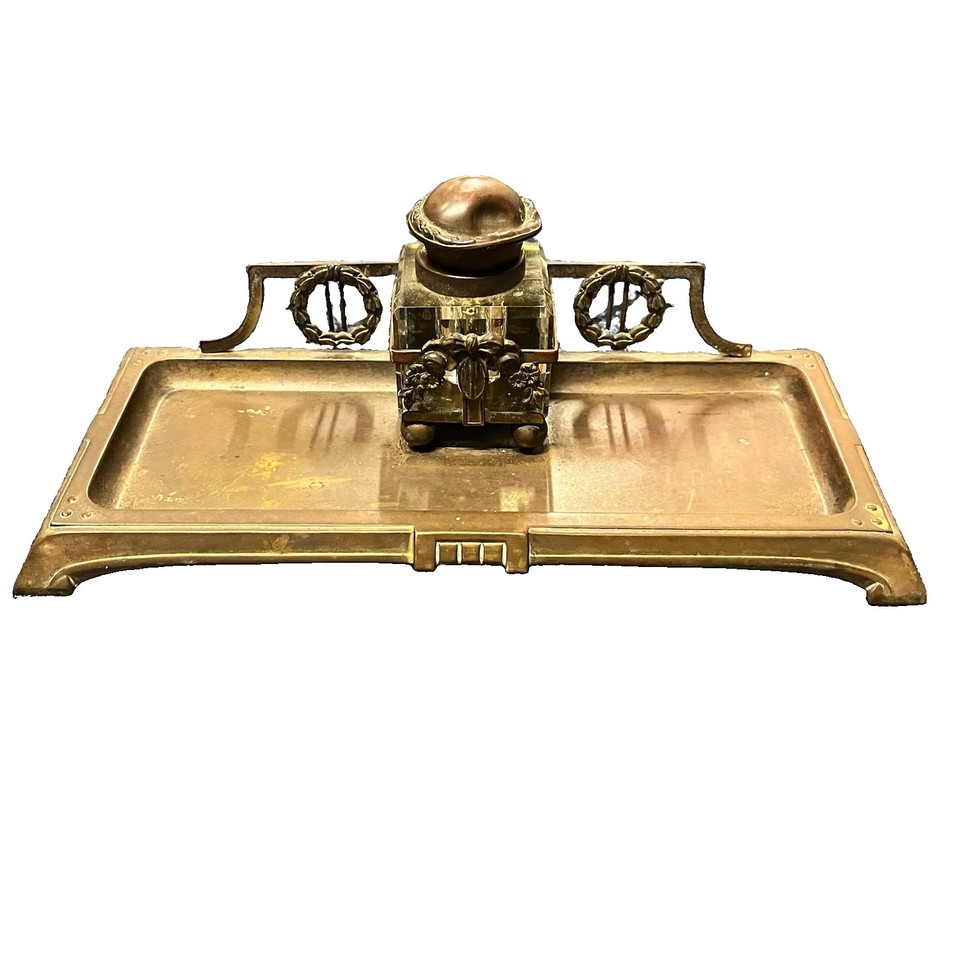 A c.1900 Edwardian brass desk stand with glass inkwell and hand-engraved ribbon-and-wreath motifs — a genuine antique artifact that transforms any desk into a statement.