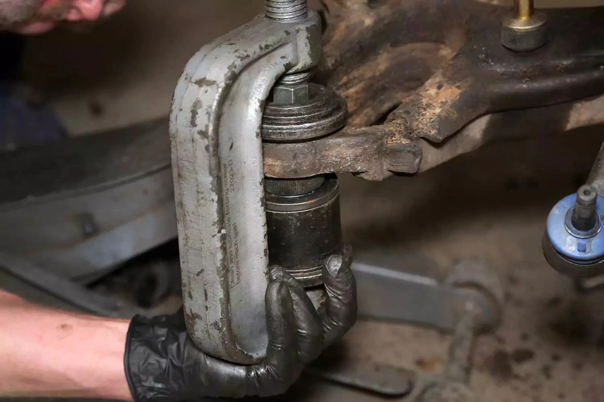 A mechanic uses a press to install the new ball joint.