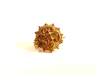 small, old, gold colored Girl Scout (''GS'') pin