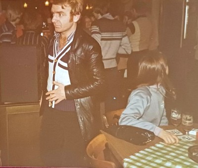 Behaarter Mann in Lederjacke im Restaurant Frau sitzt am Tisch Bier Farbfoto