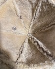 Brown shearling-lined vintage ranchero bucket hat with creased front seam and small white “R” patch on the side.