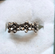 An antiqued collection of silver studs delicately coalesce into a dainty band of