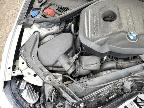 BMW 430I engine compartment with exposed suspension, wiring, and black BMW logo on side panel.