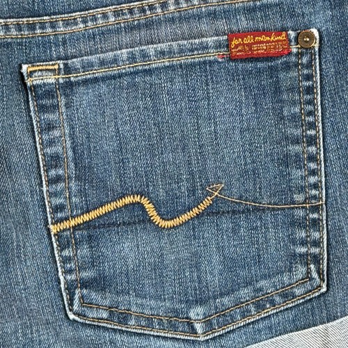 Blue stretch denim shorts, size 32, with back pocket featuring yellow stitched line and red “7 For All Mankind” patch.