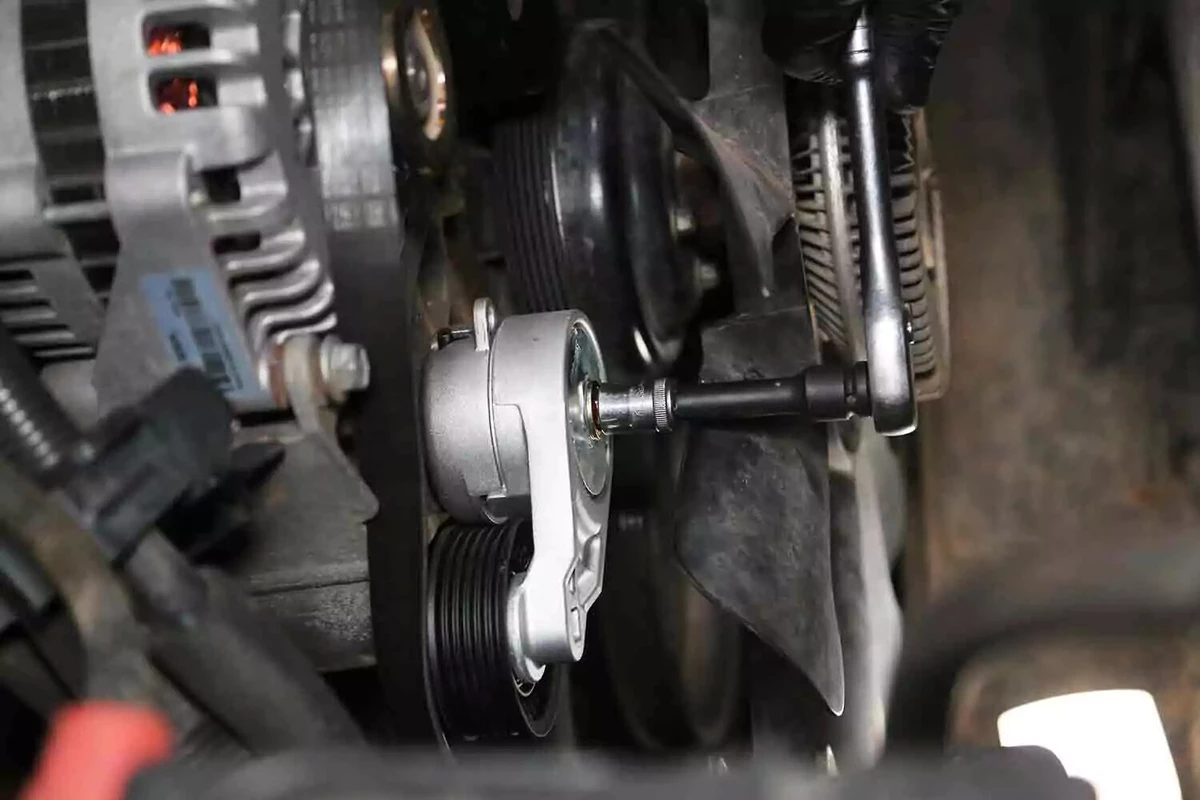 A mechanic uses a torque wrench to tighten the bolts on the new serpentine tensioner.