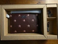 Muñequera Coach Merlot color con estrellas brillantes con 2 dijes en caja