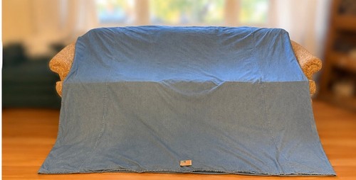 Blue denim queen duvet cover with visible seams, white fabric label reading “100% Cotton USA Made,” on a wooden floor.