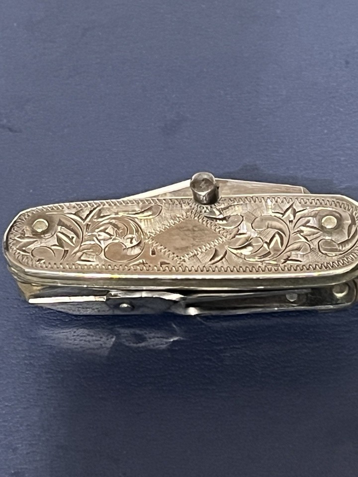 A 2-inch sterling silver multi-tool knife with hand-etched scroll work — jaw-dropping craftsmanship that doubles as wearable art.