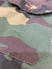 1980s vintage camouflage ranger shirt with green and brown patterns, red button, and dark green stitching on front pocket.