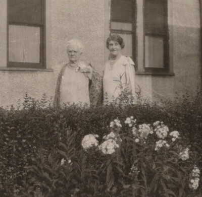 1940s Two Elderly Women Posing in Garden with Blooming Flowers Close Up