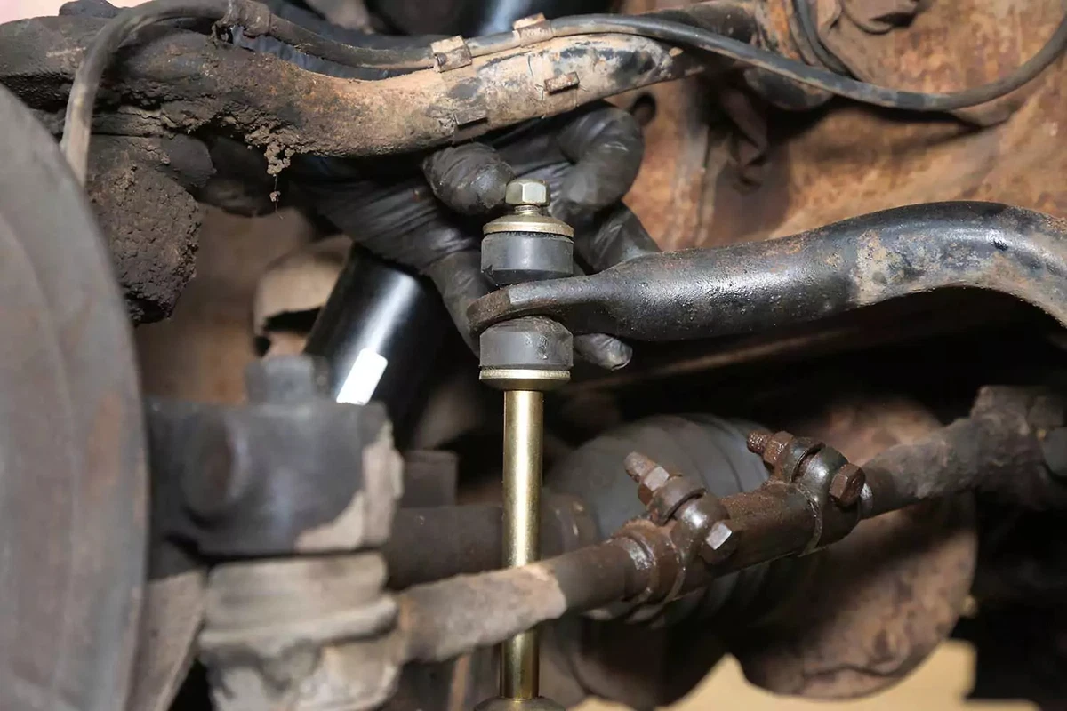 A mechanic hand-tightens the new nut on the top of the sway bar bolt.