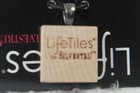 Square wooden pendant with silver metal loop, featuring white “LifeTiles” text and black “Lovestrikes” branding.