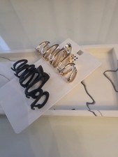Image of Matte black plastic and glossy gold-tone metal wavy hair claw clips