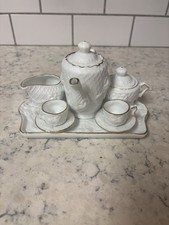 Vintage German miniature porcelain tea set with gold trim and relief decoration.