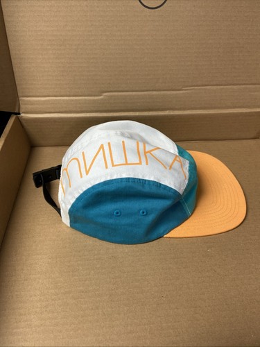 White and teal 5-panel hat with orange brim, side panels, and “MNWKA” text in white with orange accents.