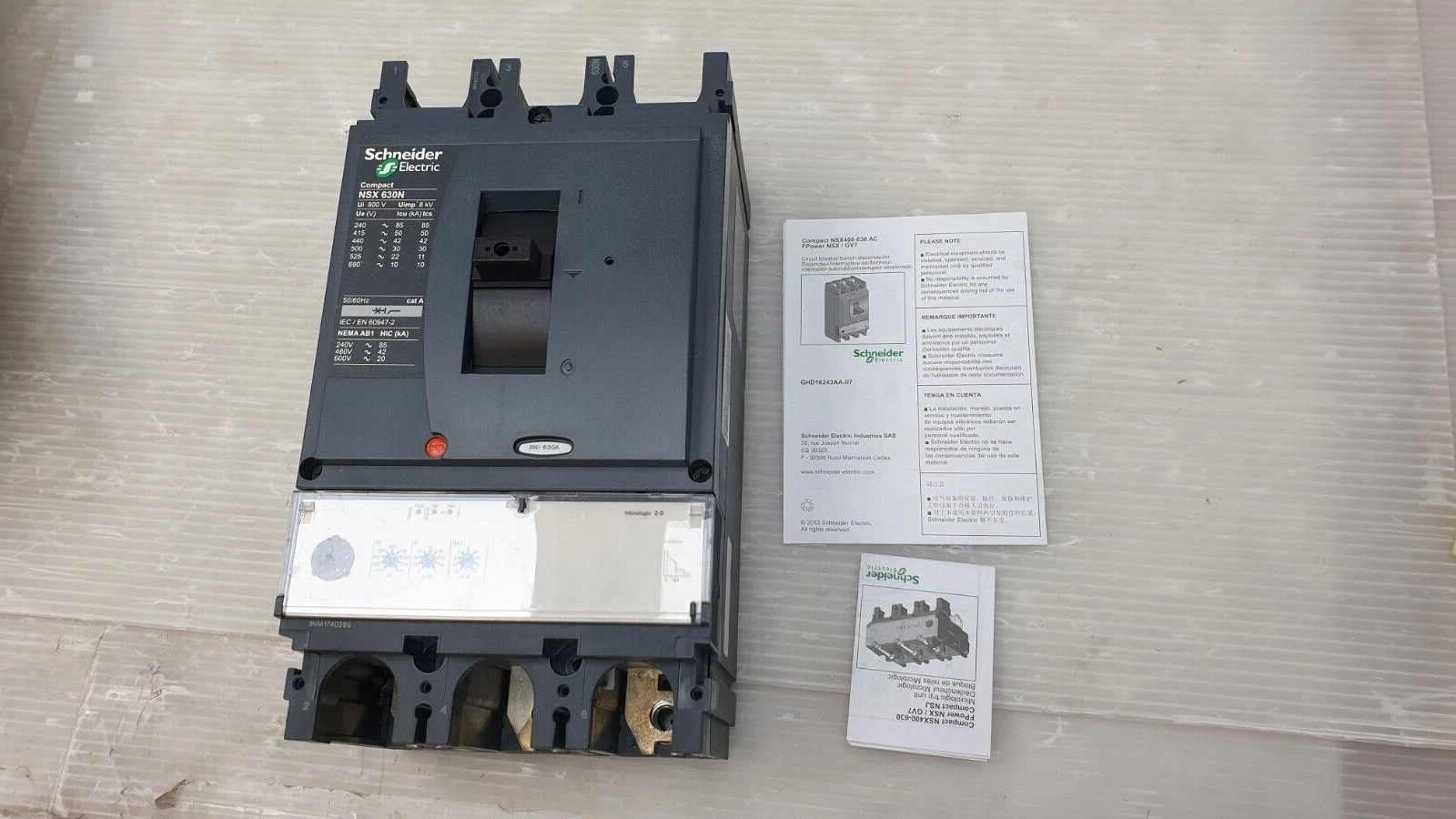 Schneider Compact NSX630N breaker with Micrologic 2.3 trip unit beside its two instruction leaflets
