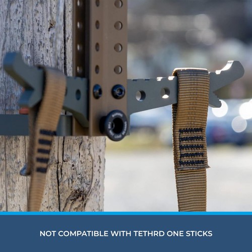Coyote-colored Step Aider with steel frame and tan straps, USA-made in two pieces, shown against a wooden tree.