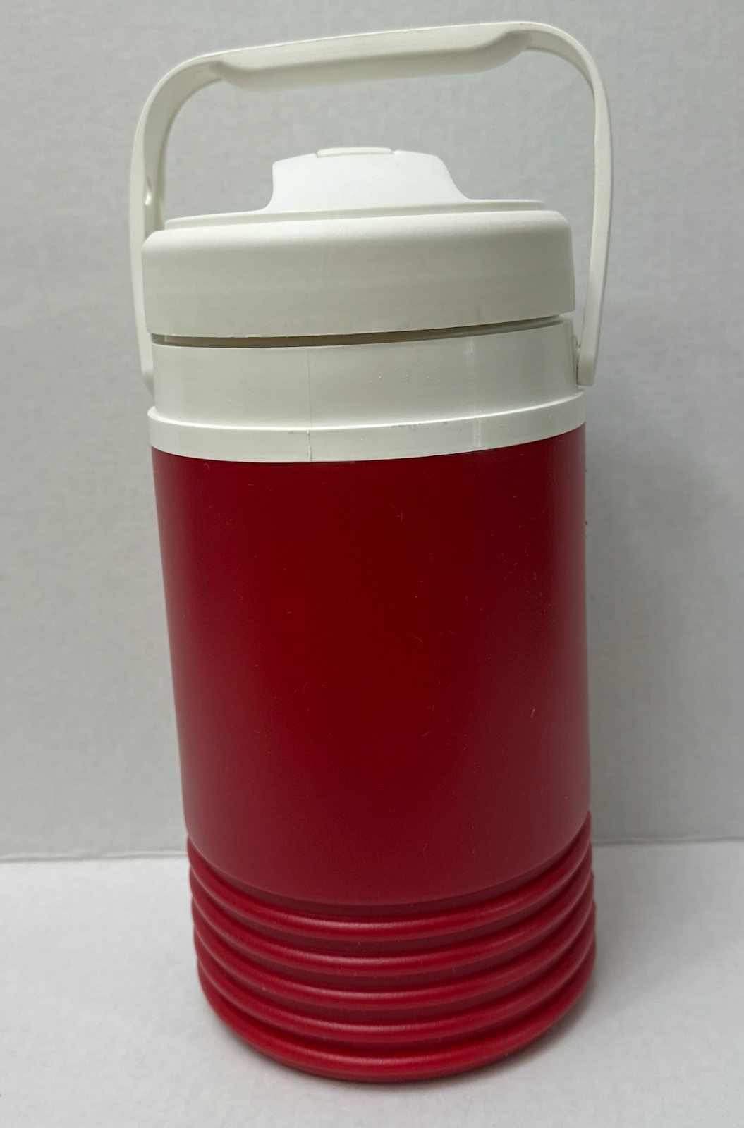 Red vintage NWT Igloo 1/2 gallon cooler with white top, horizontal band pattern, and side handle.