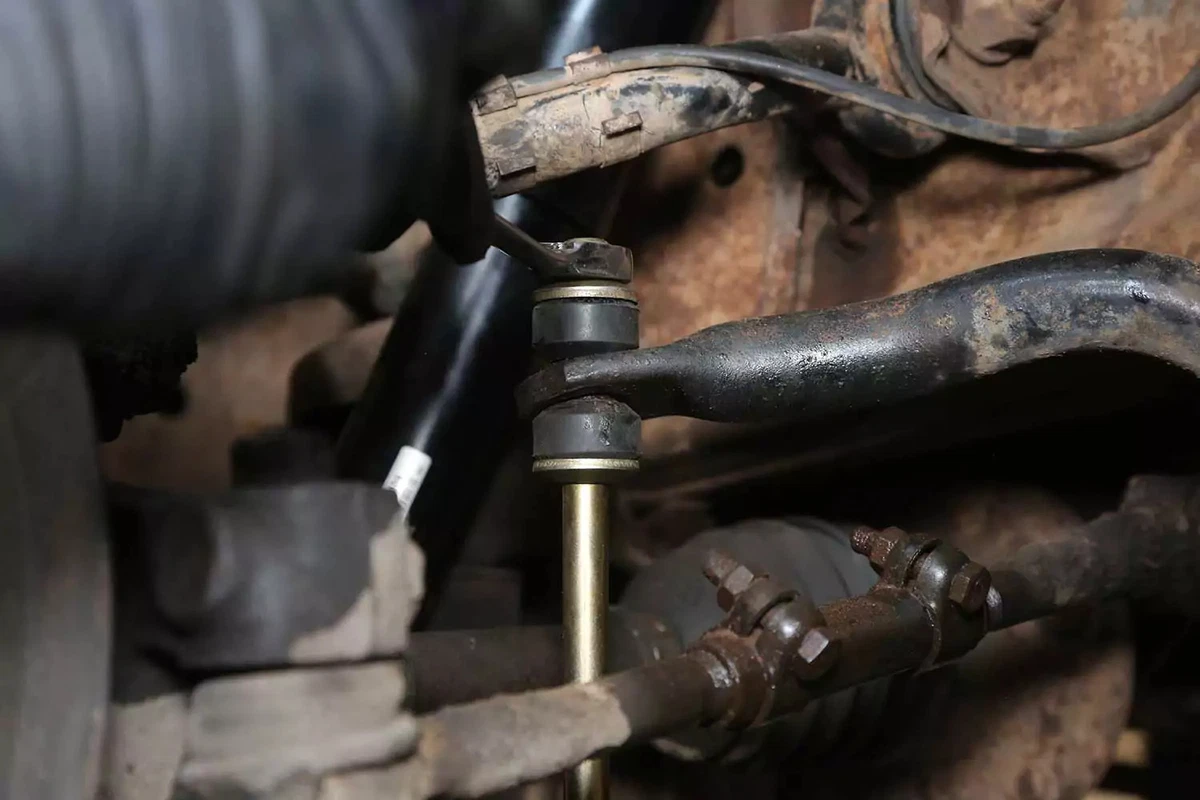 A mechanic tightens the top bolt with a wrench.