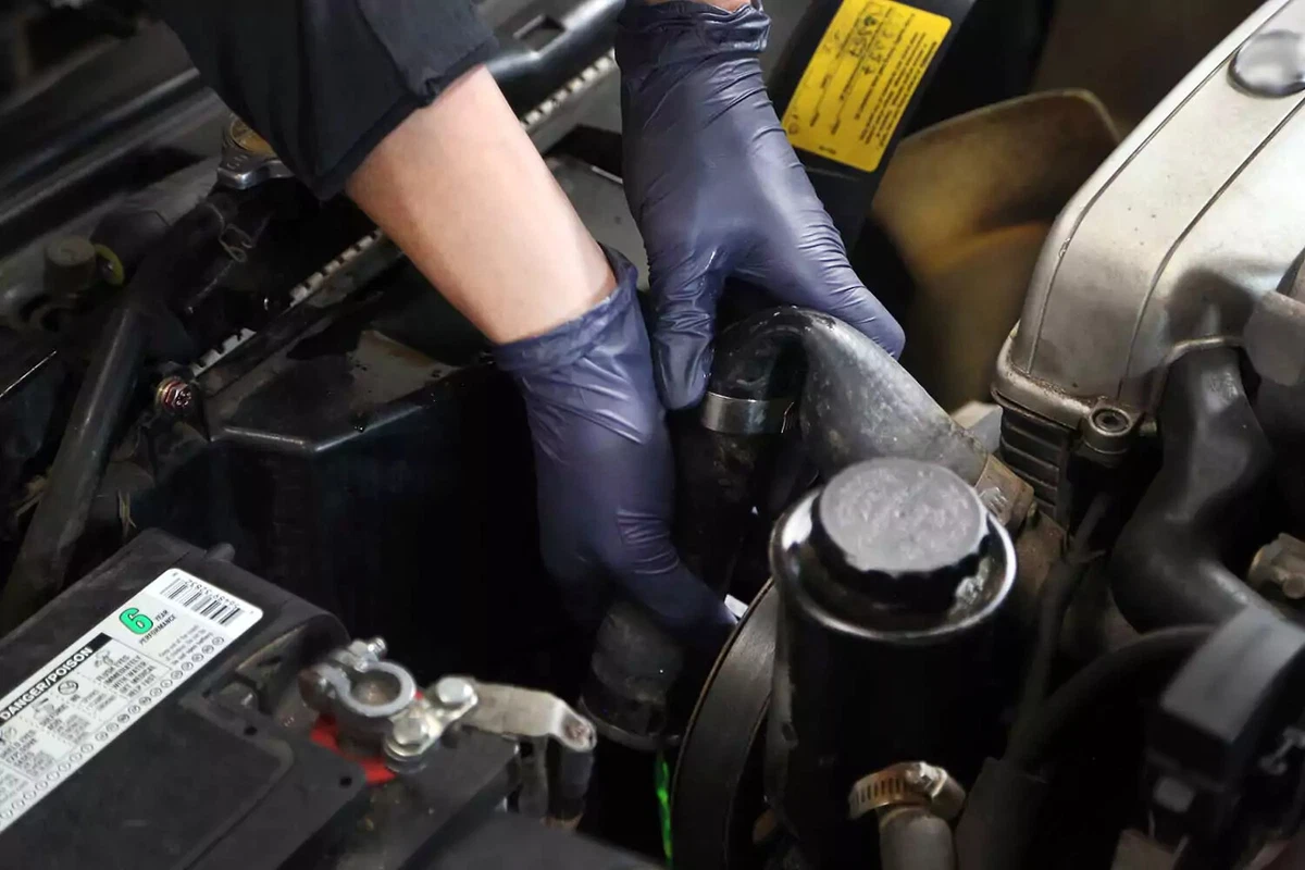 A mechanic folds a car radiator hose.
