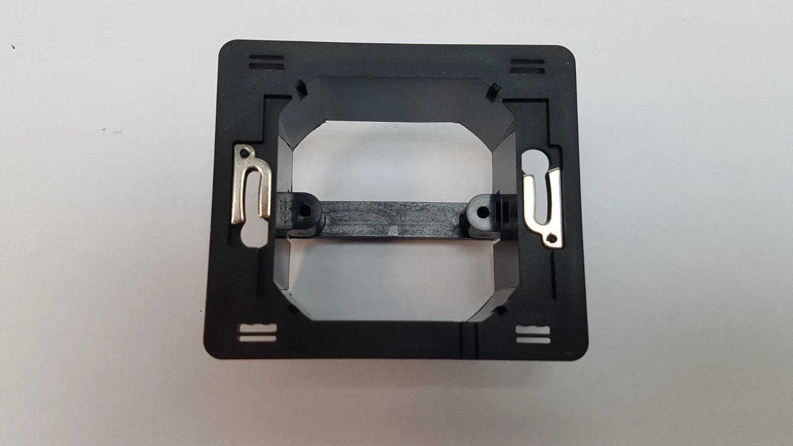 Black mounting frame with metal clips supplied with the Domintell DTDIR03-W