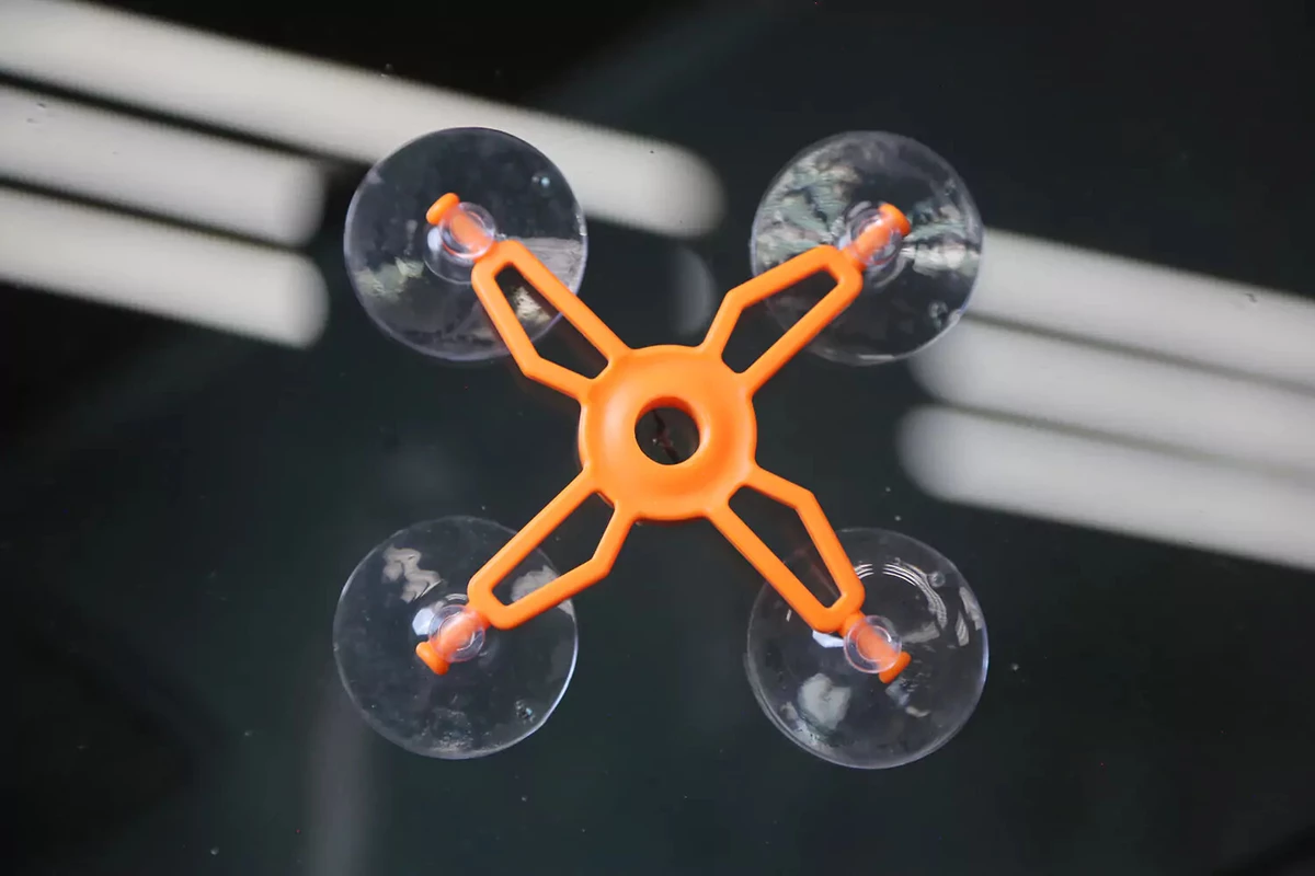 An orange repair jig with four suction cups is placed over the chip in a vehicle's windshield.