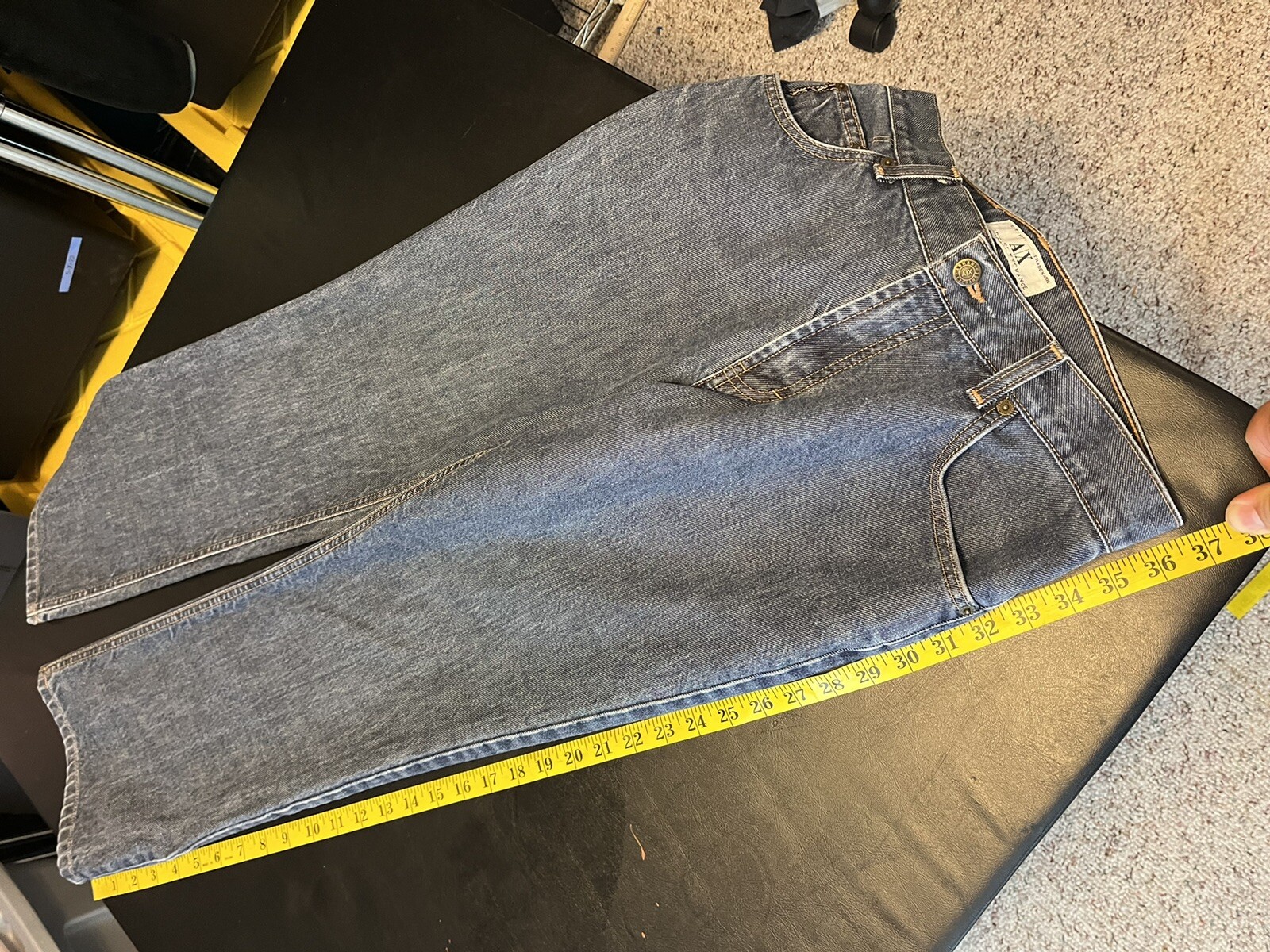 AX Armani Exchange J40 women’s blue short regular bootleg jeans with yellow measuring tape across the waistband.