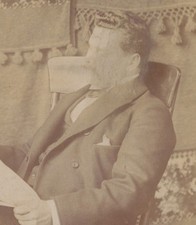 PORTRAIT OF MAN IN ROCKING CHAIR READING NEWSPAPER