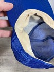 Blue Chicago Cubs snapback trucker hat with beige lining and mesh fabric, held against a person's hand.
