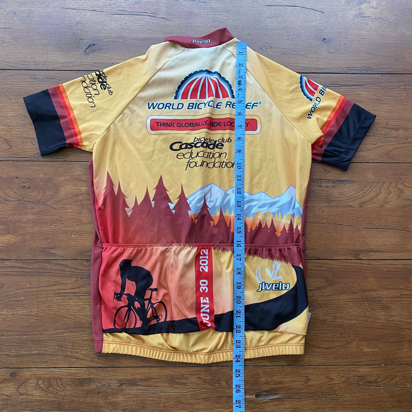 Yellow, red, and black JLvelo men’s 2012 cycling jersey with mountain and forest graphic, “Think Globally Ride Local” text, and sponsor logos.