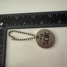The Sak Bag Purse Charm Keychain Silver Tone Logo Circle Pendant