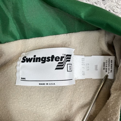 White fabric tag on green and tan Pioneer Seeds Swingster jacket with black “NAME” text and USA flag graphic.