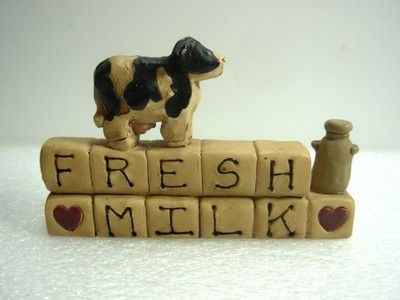 Ungewöhnliches 3D Schild in Form einer Kuh und Milchkanne an einer Wand. Frische Milch. Suzi