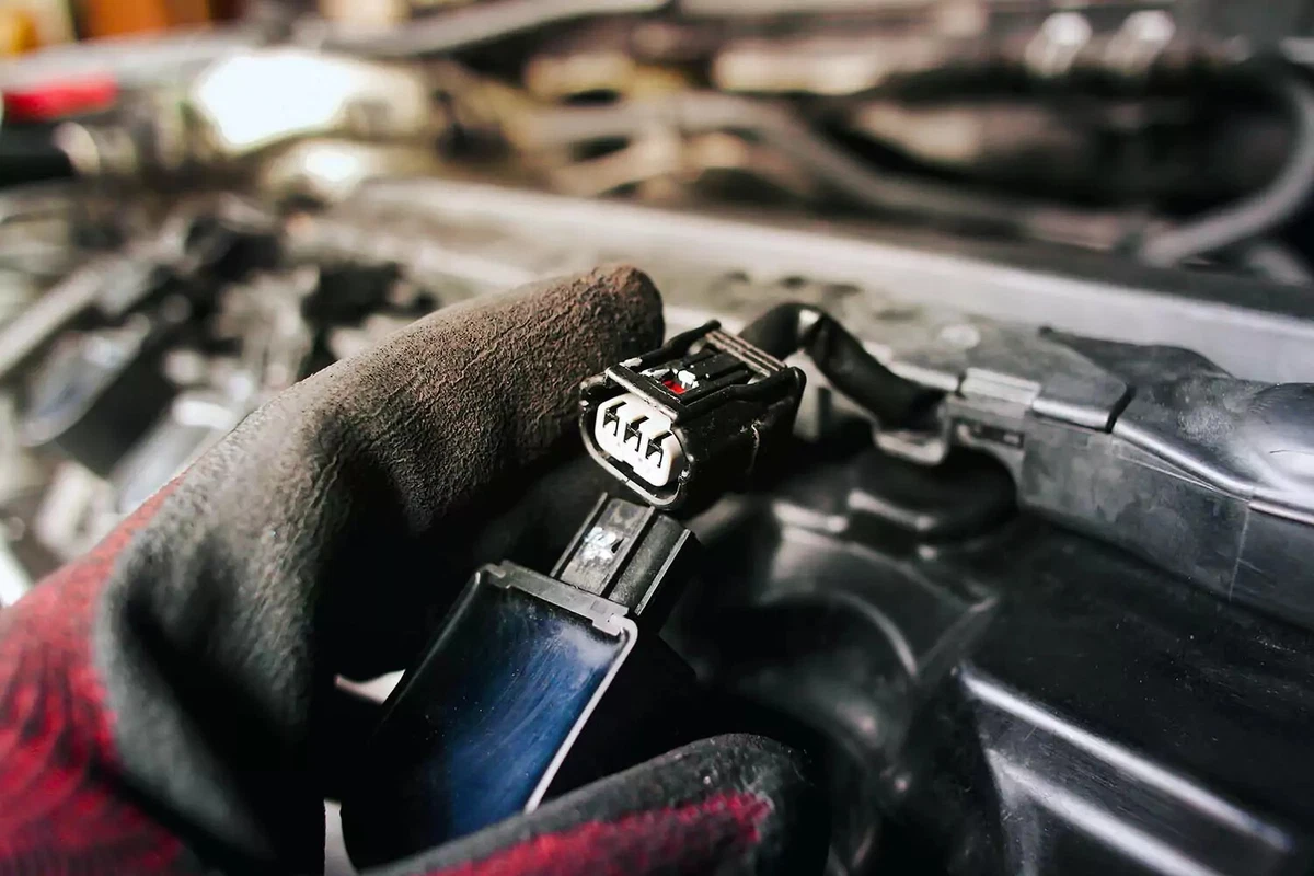 An auto mechanic unplugs an ignition coil as part of an ignition coil replacement.