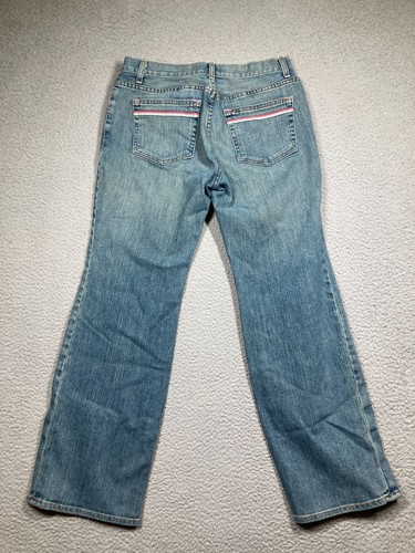 Blue stretch light wash Karen Kane women’s jeans with pink and red stripe details on back pockets, laid flat on gray surface.