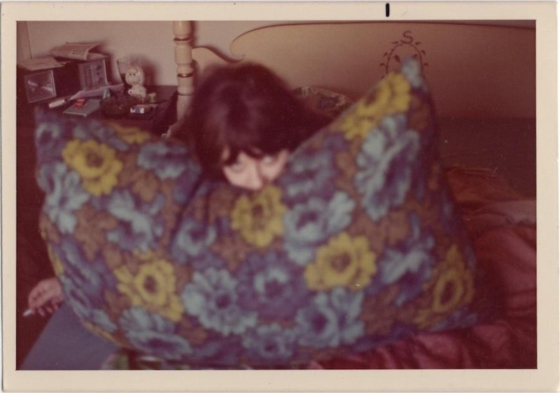 Woman on bed hiding behind pillow, 1960s