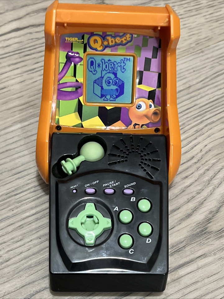 A rare 2000s Tiger Electronics Q*bert handheld — a micro-arcade relic of a nearly forgotten franchise that's pure shelf candy for retro collectors.
