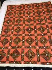 Vintage quilt featuring a vibrant orange and dark patterned geometric design.