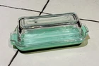 A Fire King jadeite butter dish with a clear glass lid