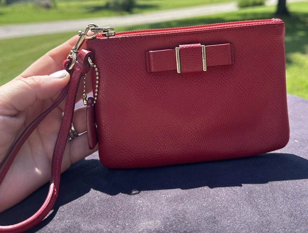 Polso Coach rosso con fiocco. Chiusura con cerniera. Cinturino da polso. Pulito.