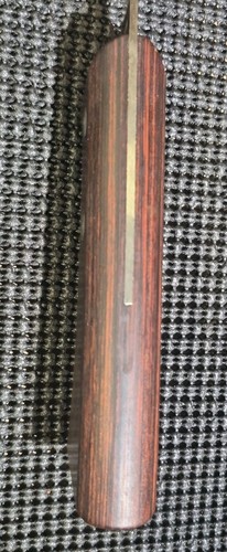 Vintage WESTERN fish fillet knife with red wood grain, gold center line, and flat rectangular sheath on black background.