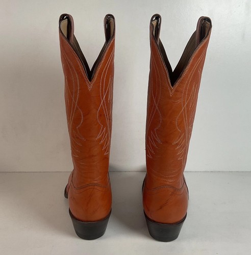 Brown leather cowboy boots with pointed toes, white stitching, and dark brown heel accents on tall shafts.