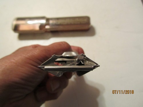 Silver vintage Playtex hair cutter with triangular blade and engraved oval case, held by hand against white background.