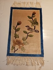 "A small decorative rug with a classic bird and flower design, 19x12 inches