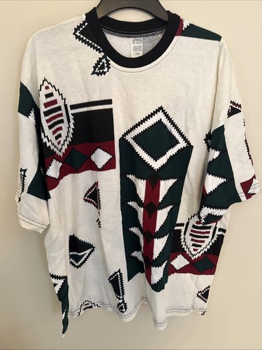 White vintage T-shirt with black, green, and red geometric shapes and leaf accents, made in the USA.