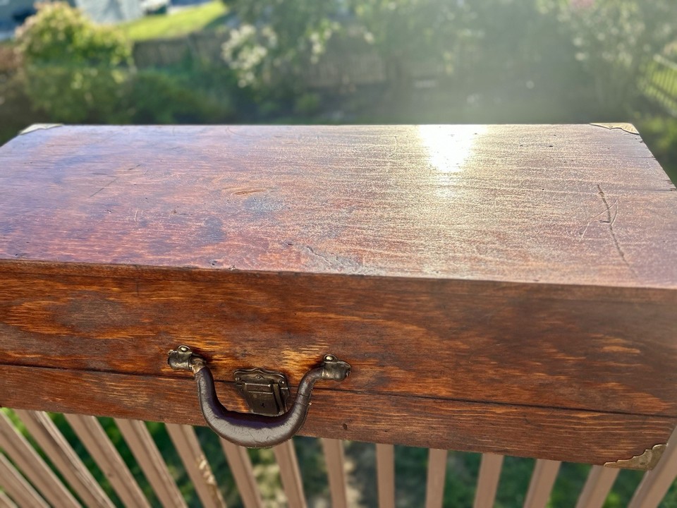 A dovetailed oak lap desk box with brass corners and leather handle — hand-crafted joinery on a writing box that doubles as a display piece.