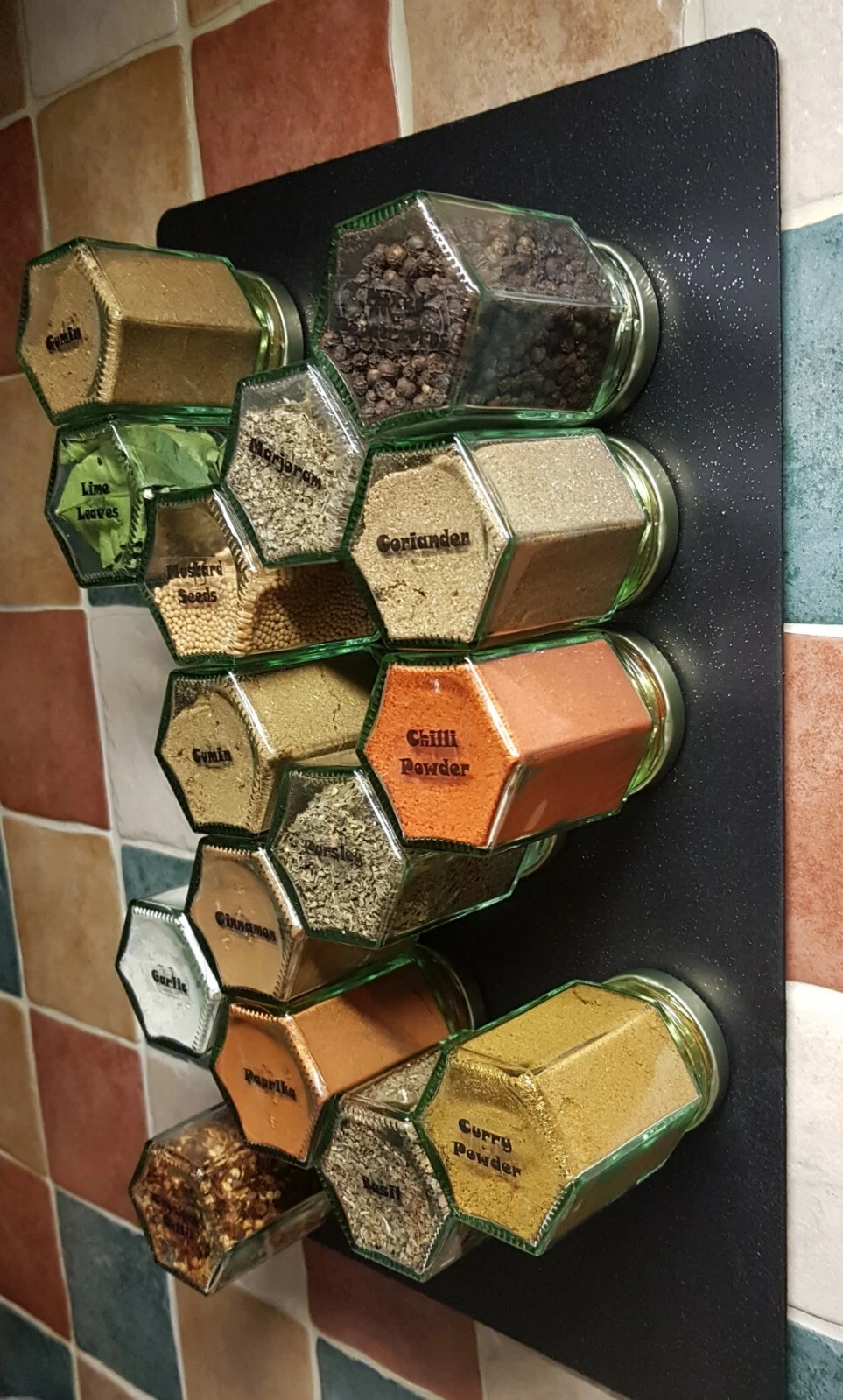 Magnetic spice rack with airtight jars on black sparkly sheet. Wall mounted.