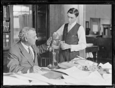 Mr Mares from the Weather Bureau at his desk having a drink served - Old Photo