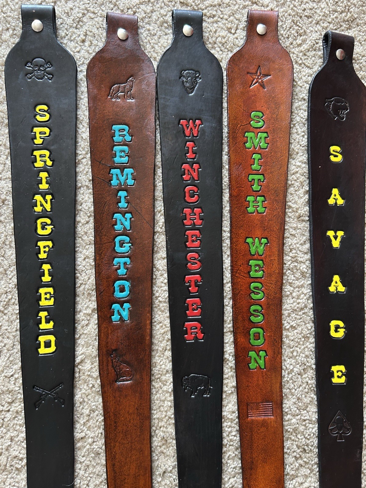 Brown leather rifle sling with black and red text, including “Springfield,” “Remington,” and “Savage” in bold letters.